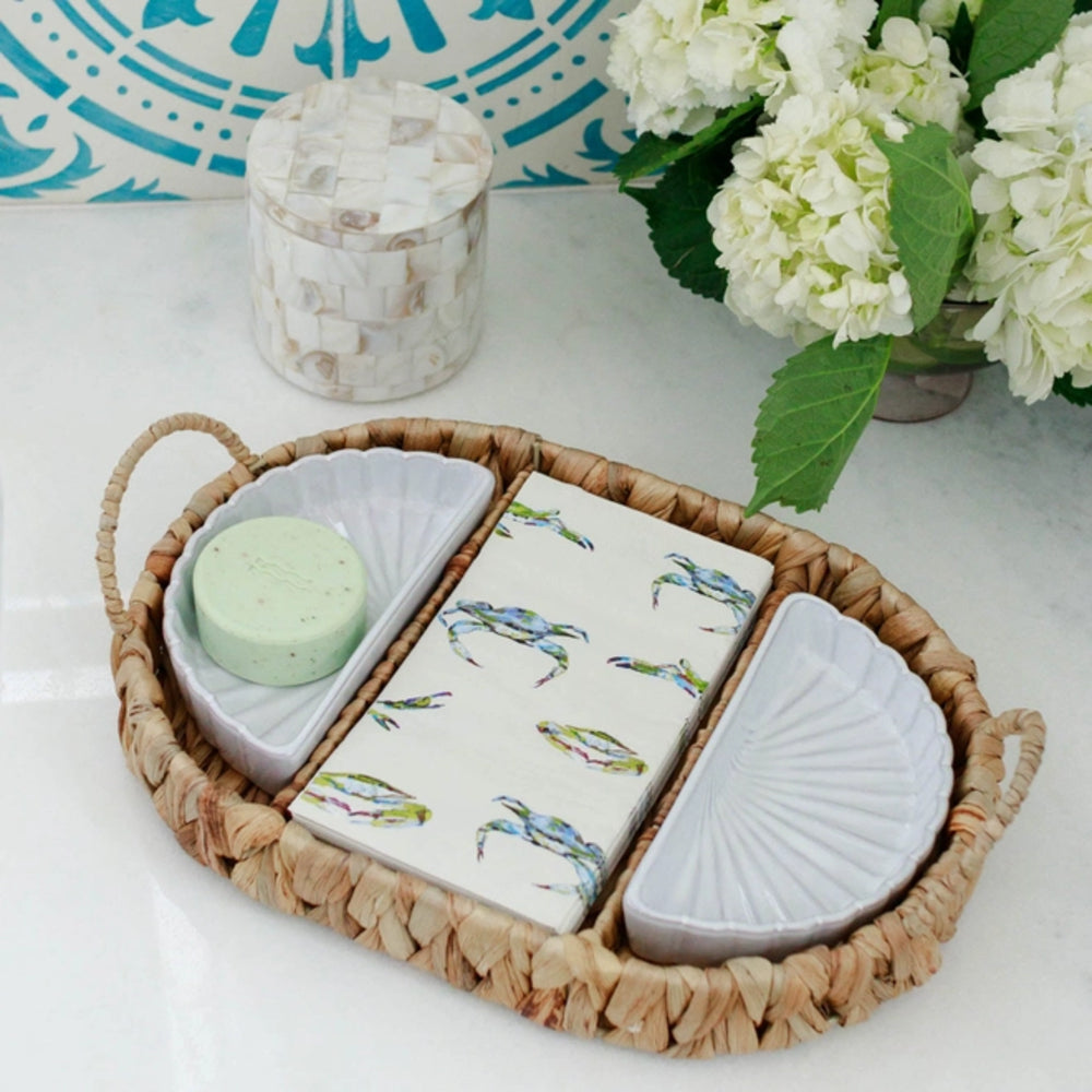 Decorative items including a soap dish with crab design, a green bar of soap, and a shell-shaped container on a woven tray.