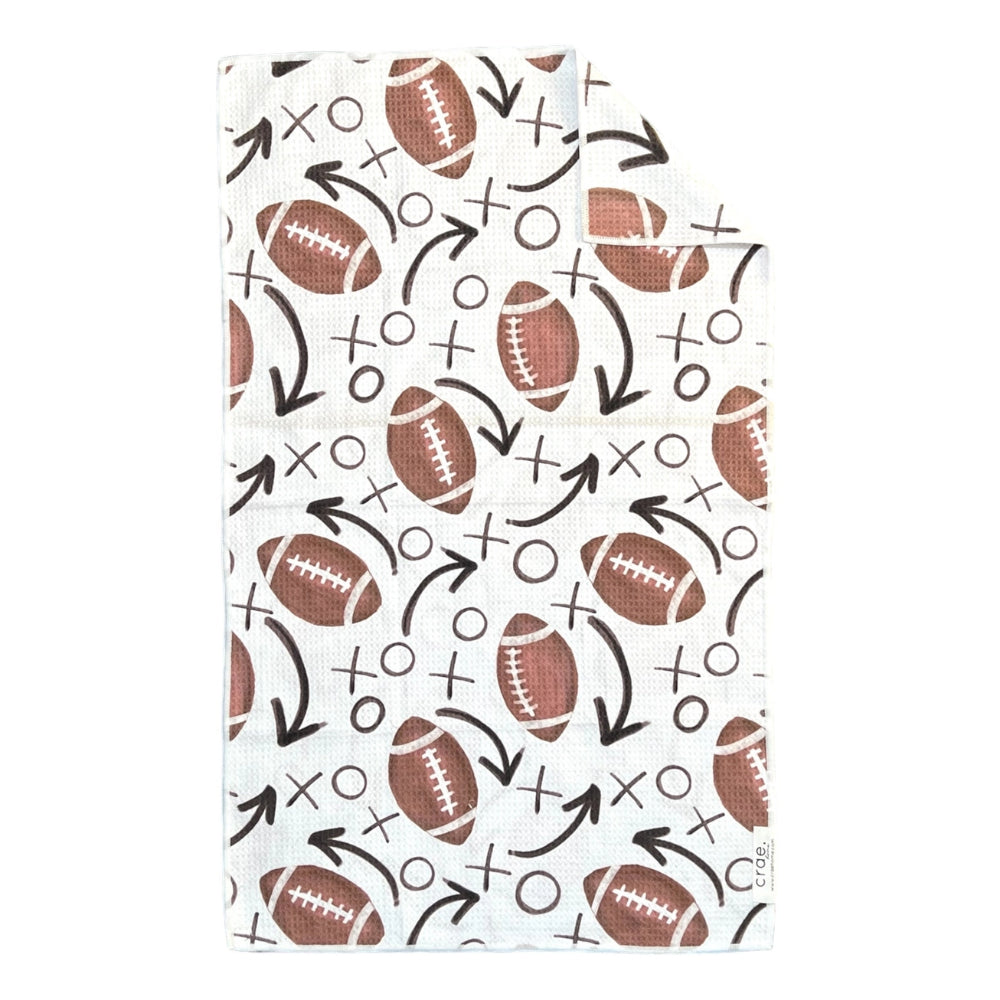 A white hand towel with xo and football designs on a white backround. 