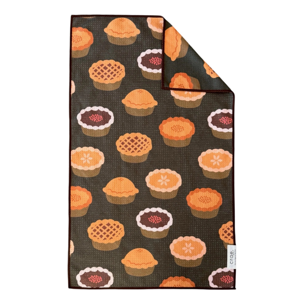 A black hand towel with pie designs on a white backround. 