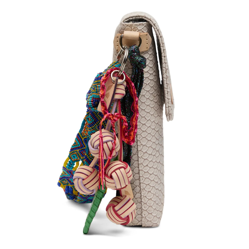 Colorful keychain with decorative elements attached to a beige textured bag on a white background