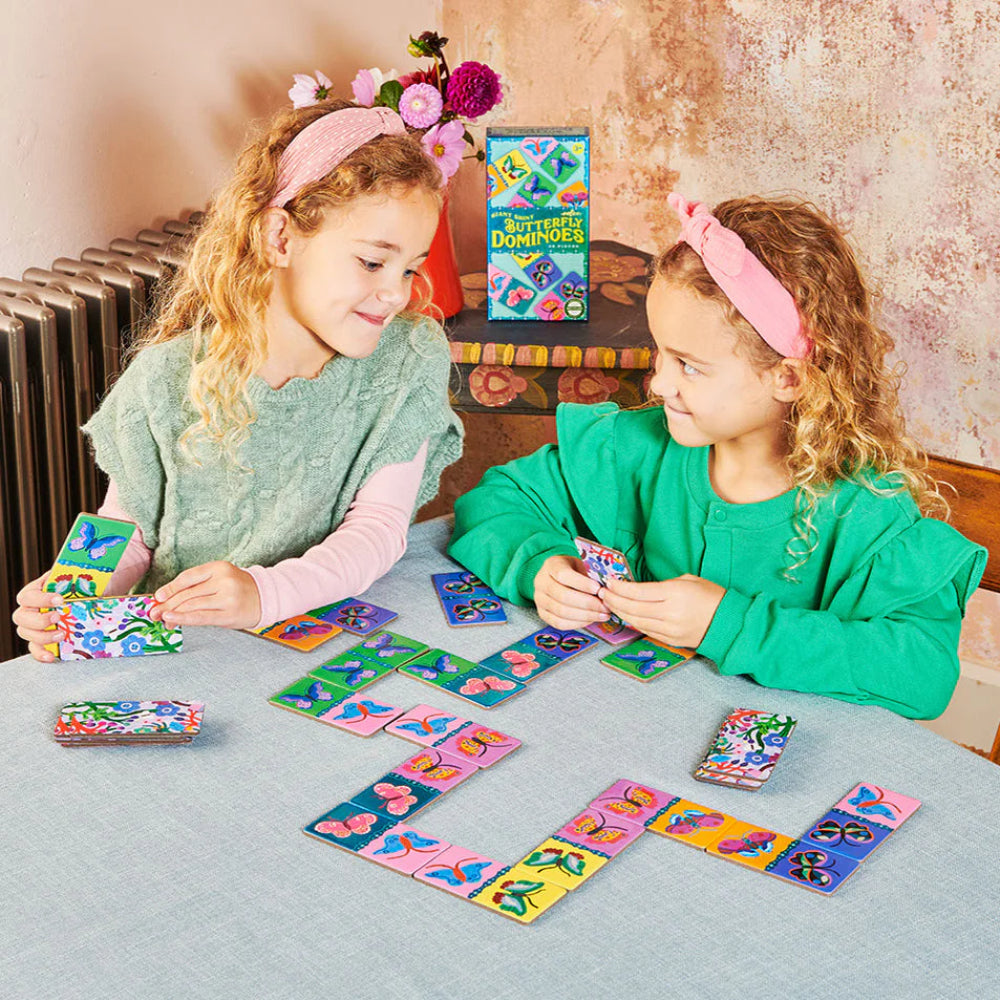 Two children playing with colorful dominoes on a table.