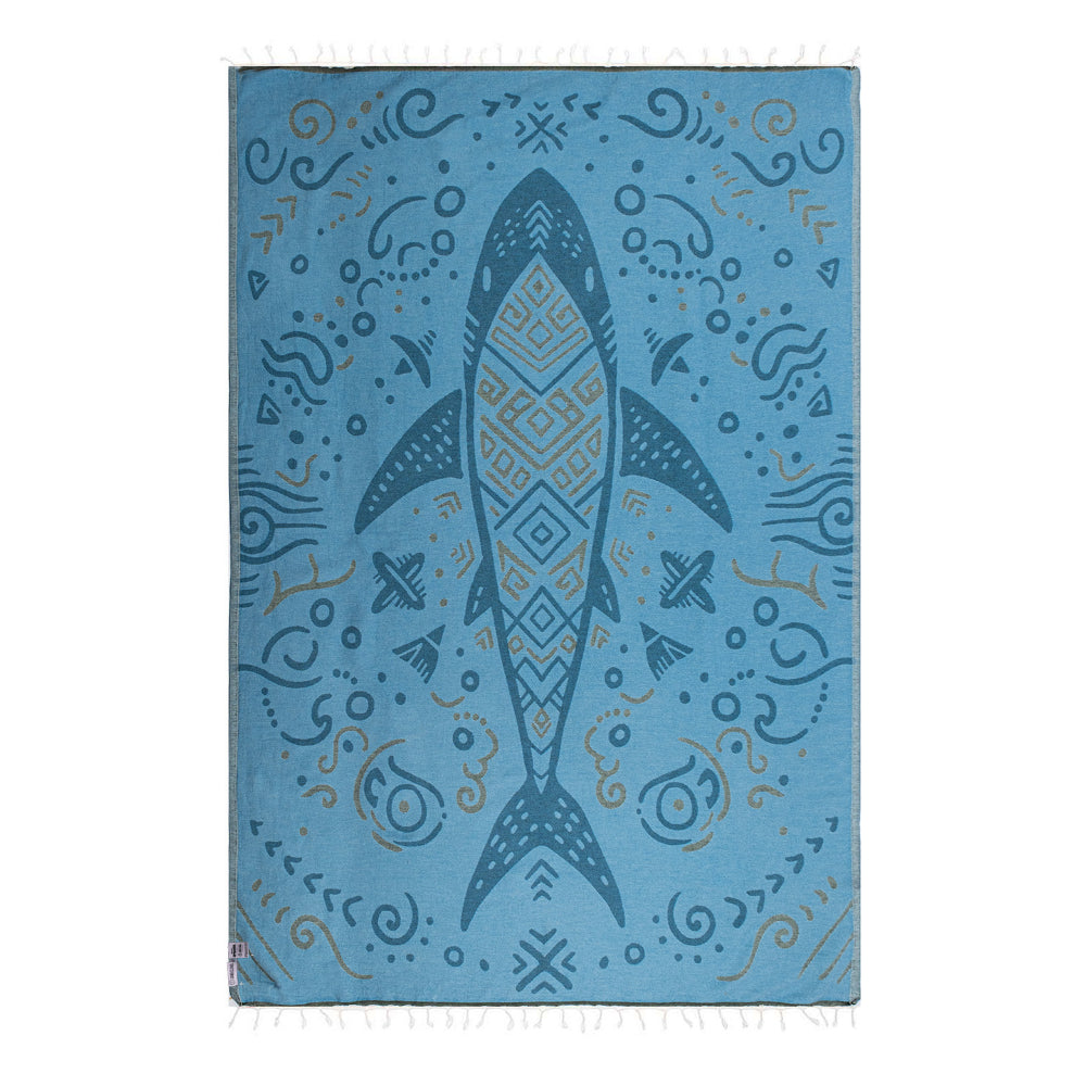 Side two of a gray & blue  beach towel with a shark design with blue & beige abstract patterns and a white tassel edge on a white background.