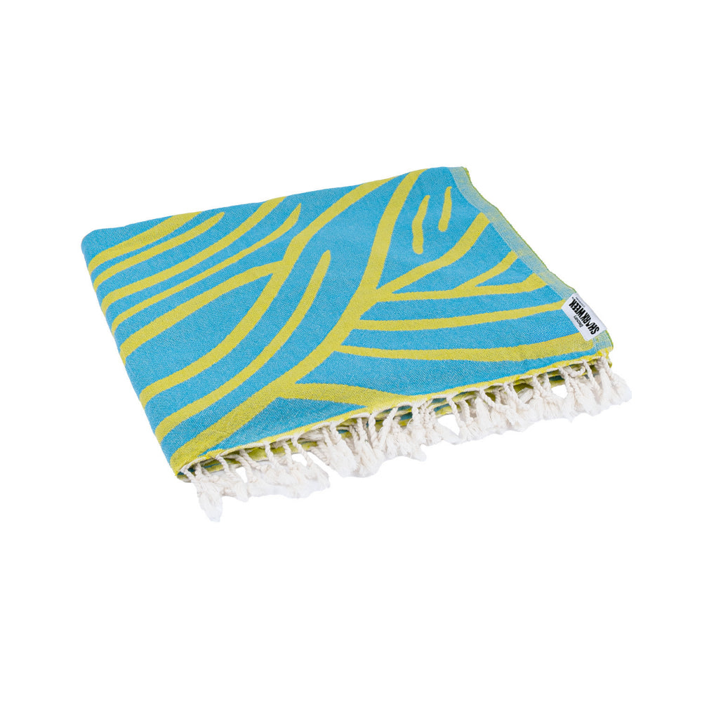 A folded beach towel with a blue and yellow shark design with a white tassel edge on a white background.