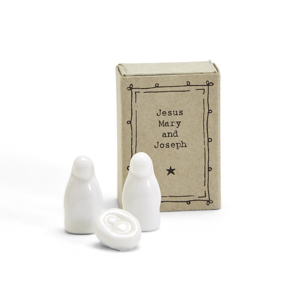 White ceramic figures in front of a 'Jesus Mary and Joseph' box on a white background.