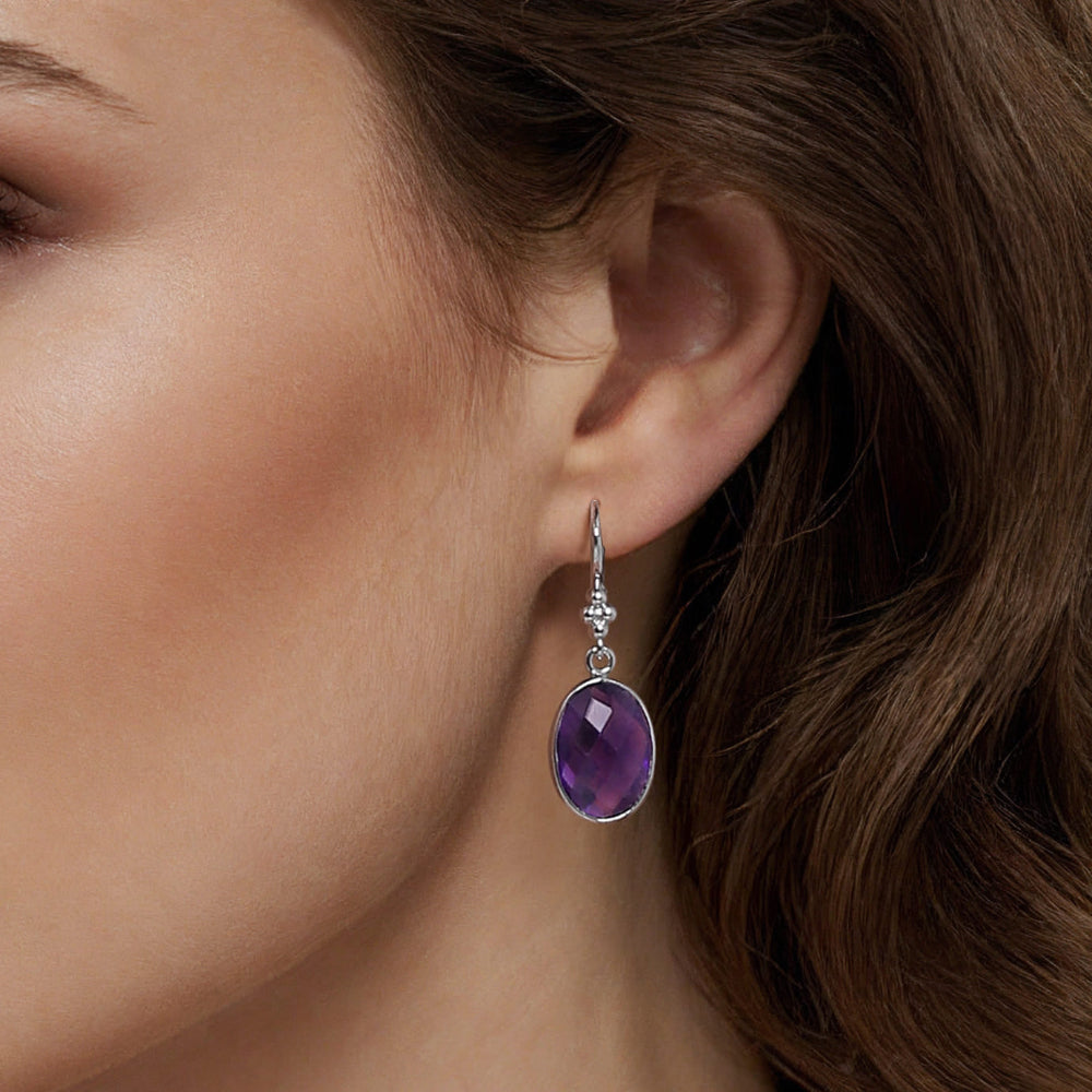 Close-up of a woman wearing Amethyst drop earrings.