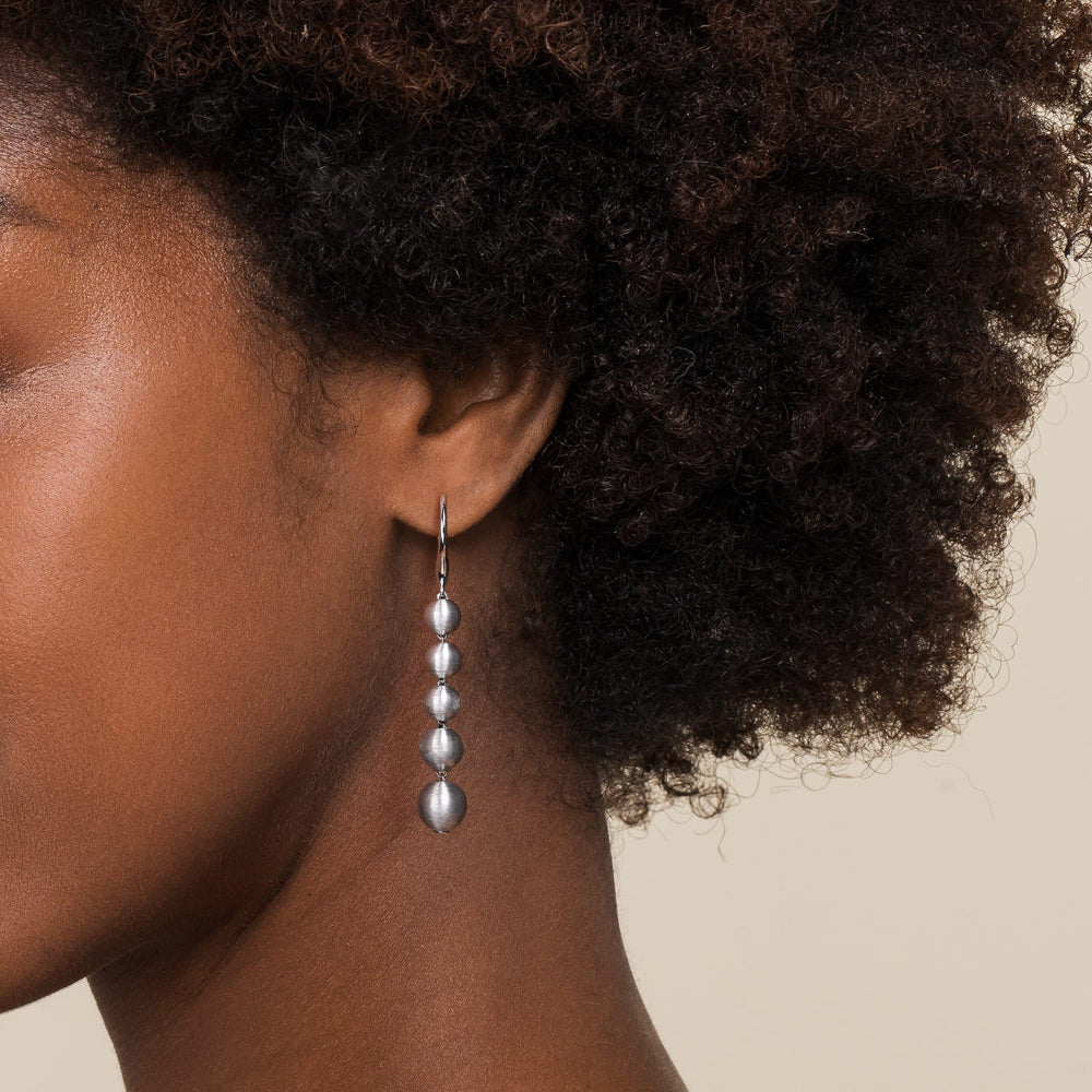close up of woman wearing silver drop earring 