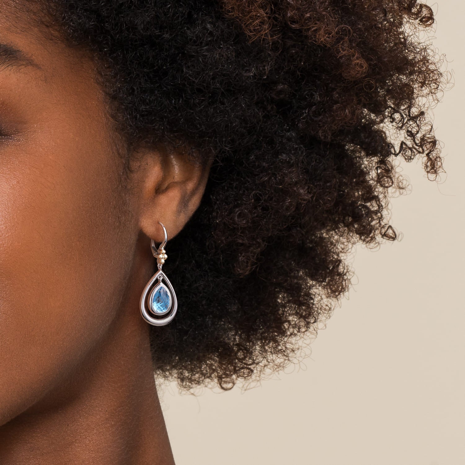 Close up woman wearing silver and gold blue topaz drop earring 
