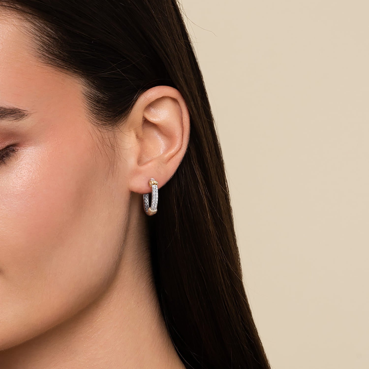 Close-up of a woman wearing a silver  and gold hoop earring 