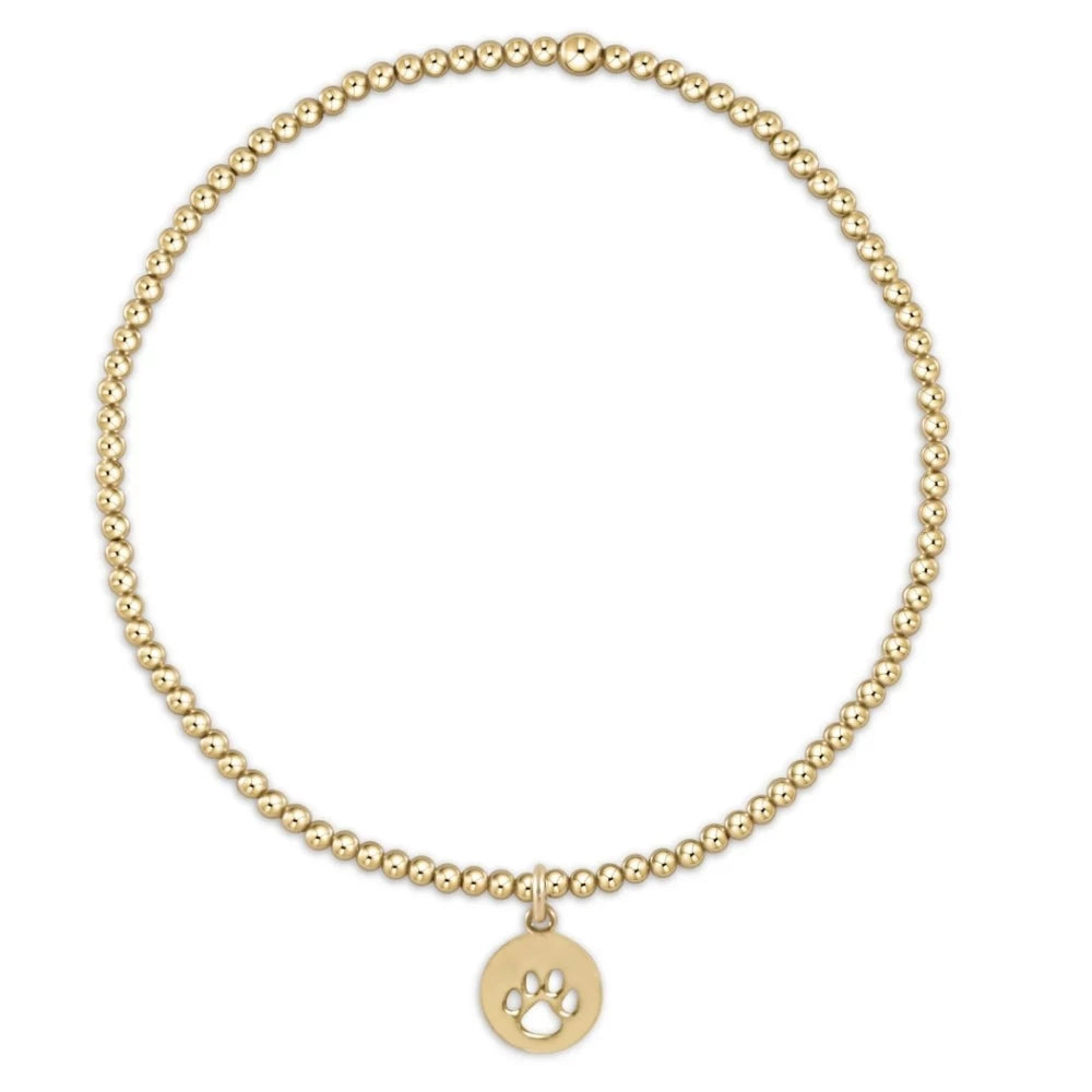 Gold beaded bracelet with a paw print charm on a white background