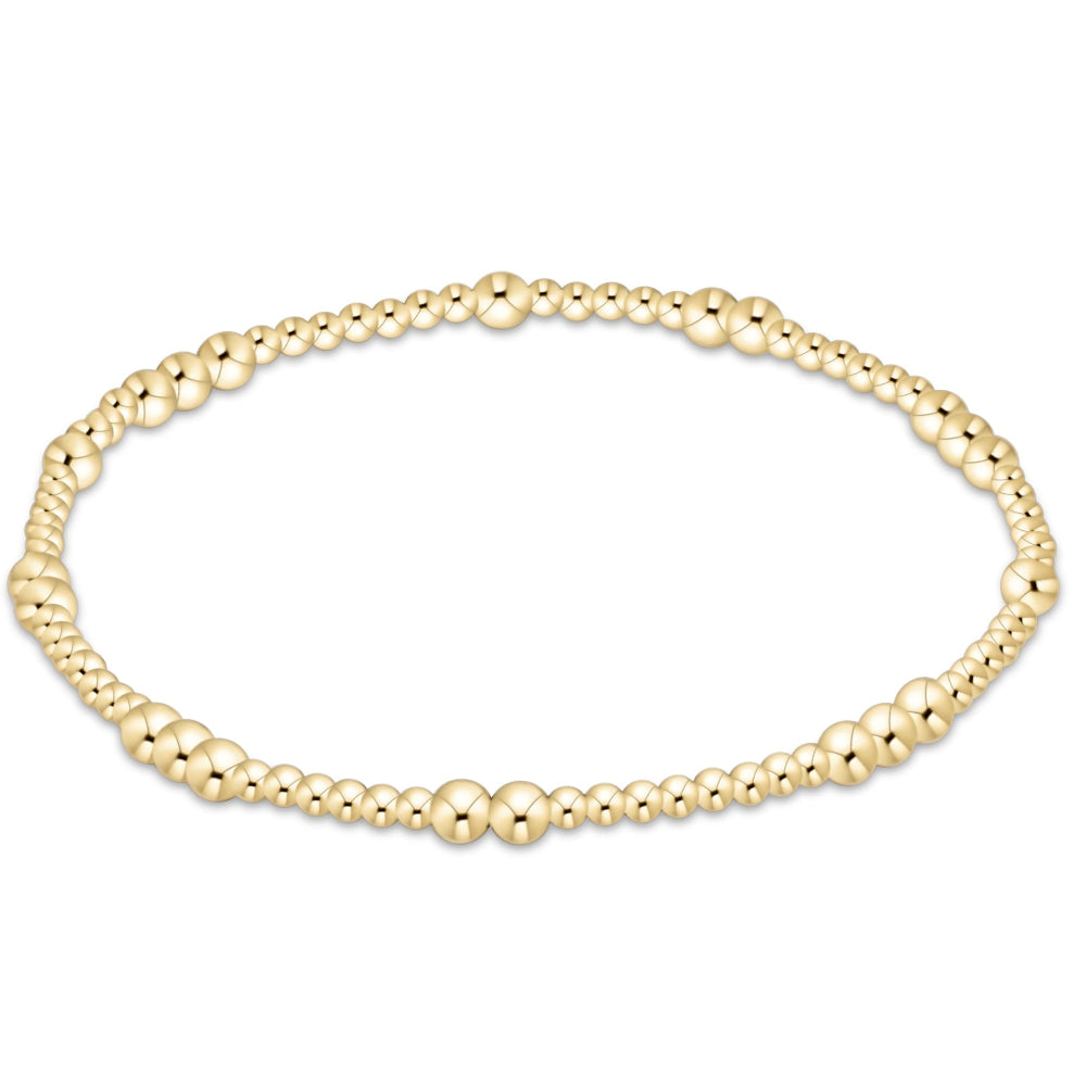 A gold beaded stretch bracelet with alternating large and small polished beads, arranged in a horizontal oval on a plain white background.