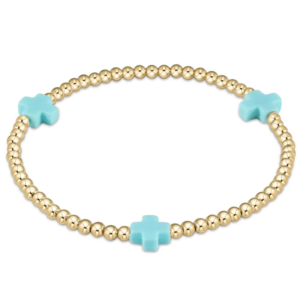 Gold beaded bracelet with turquoise cross charms on a white background