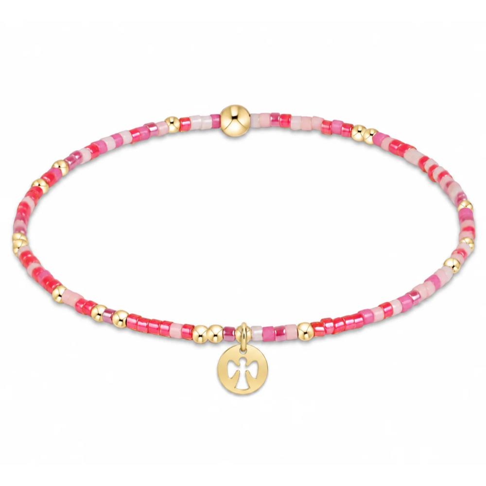 A delicate beaded bracelet featuring pink and red translucent beads, accented with small gold spacer beads and a gold circular charm with a cross cutout, displayed on a clean white background.