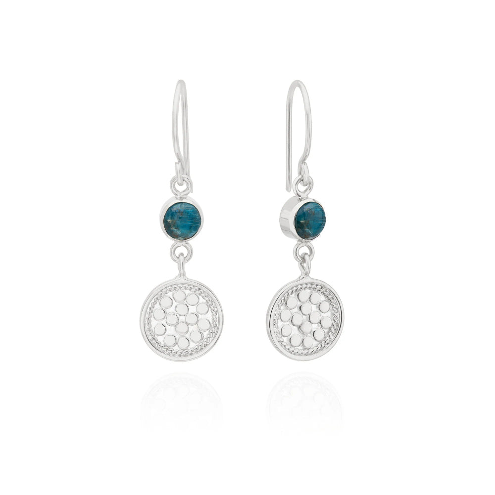 A pair of silver drop earrings featuring a small round dark blue stone above a larger textured circular silver pendant