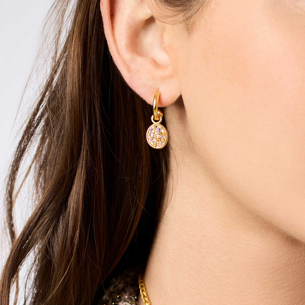 Gold earring worn by a person with a neutral background