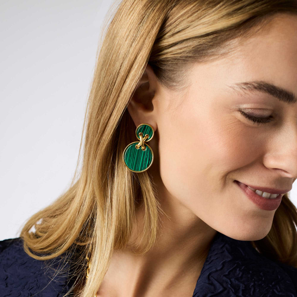 Close-up of a woman wearing green earrings with a white background