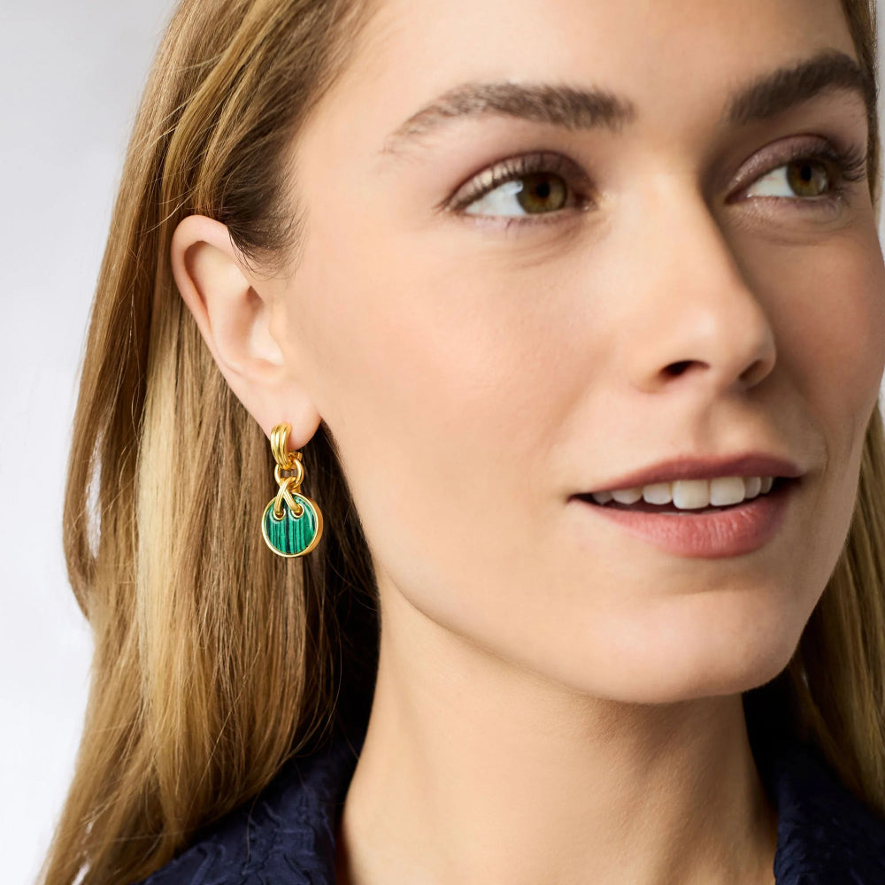 Close-up of a woman wearing gold earrings with green accents.