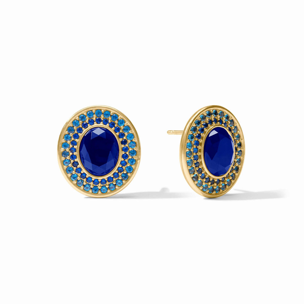 A pair of gold oval stud earrings featuring a central deep blue oval stone surrounded by a halo of small bright blue stones, shown on a clean white background.