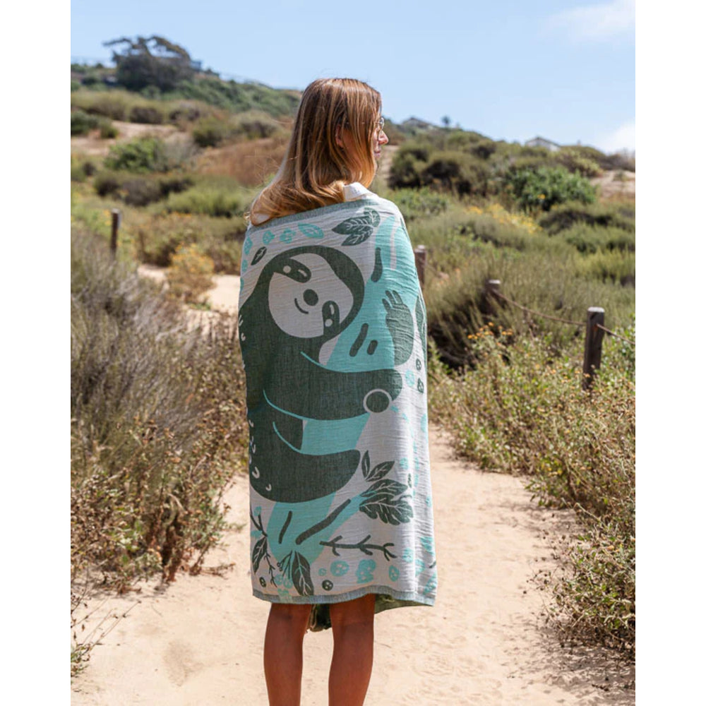 Person wrapped in a towel with a cartoon character design, standing on a path in a natural setting.