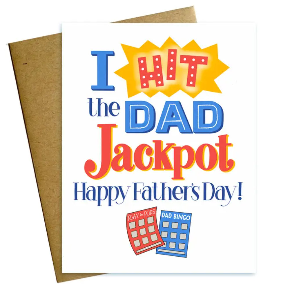 A vertical printed greeting card with the text 'I HIT the DAD Jackpot Happy Father's Day!' featuring graphic elements such as a trophy and dice, and a kraft envelope. 