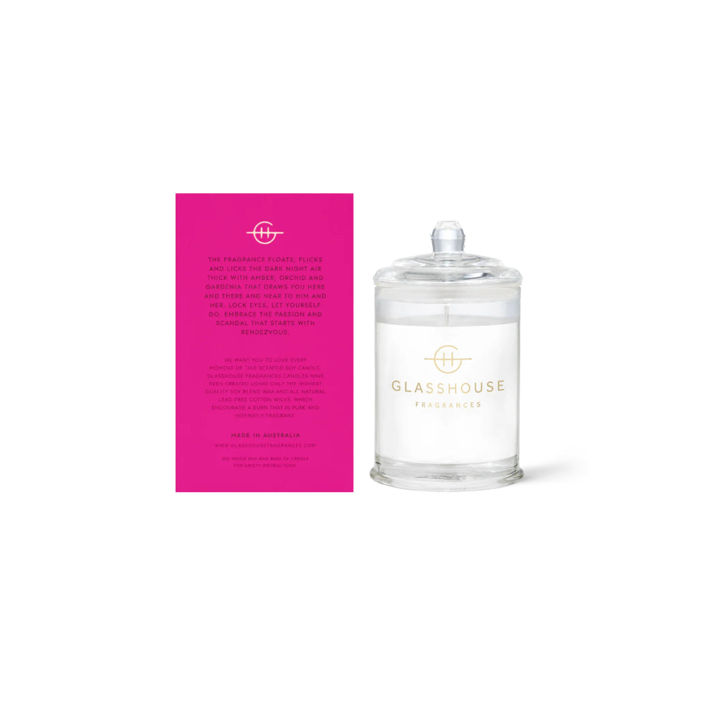 The back of a glasshouse candle pink packaging with text and a clear 'Rendezvous' candle  on a white background.