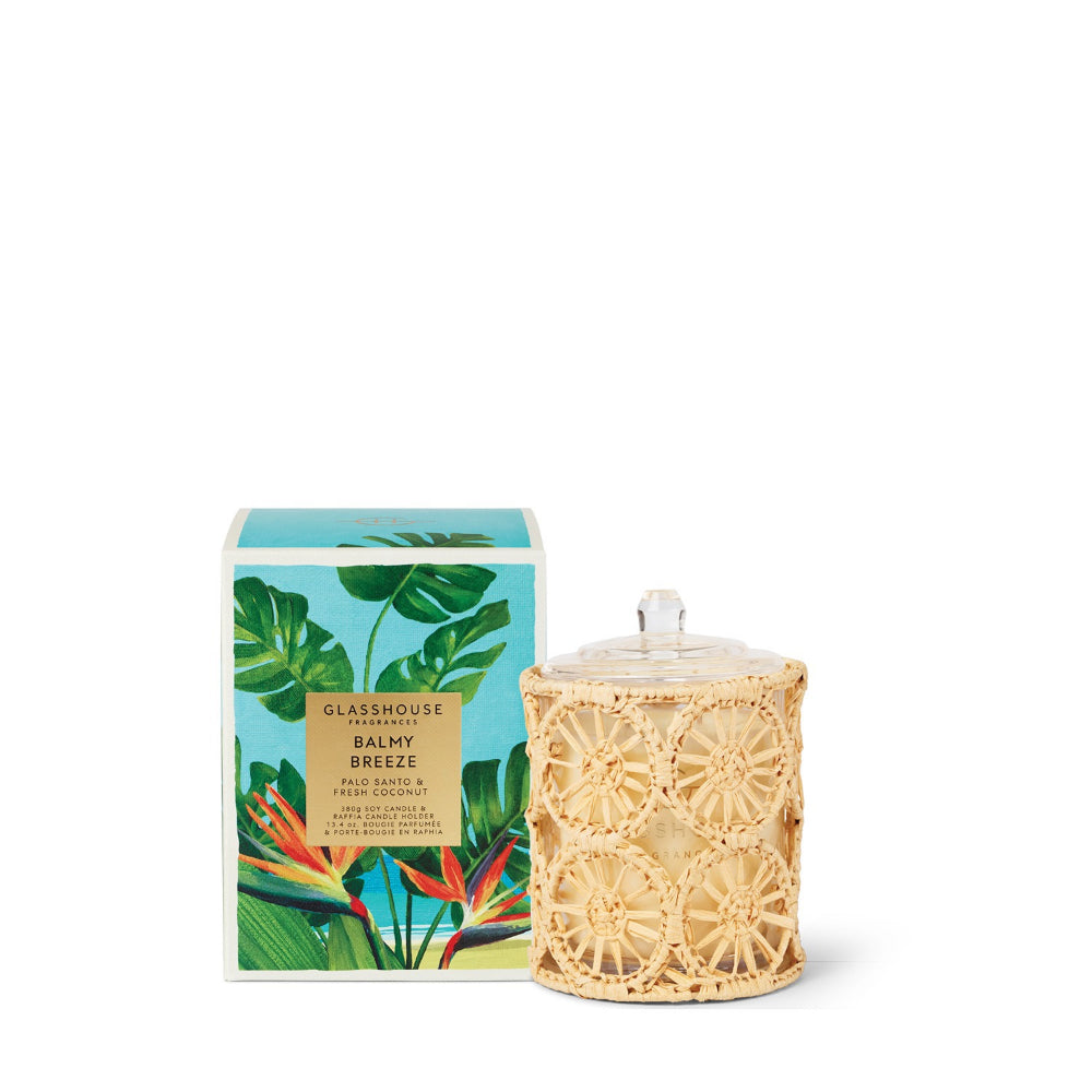 Candle with wicker lid and decorative packaging featuring tropical plants on a white background