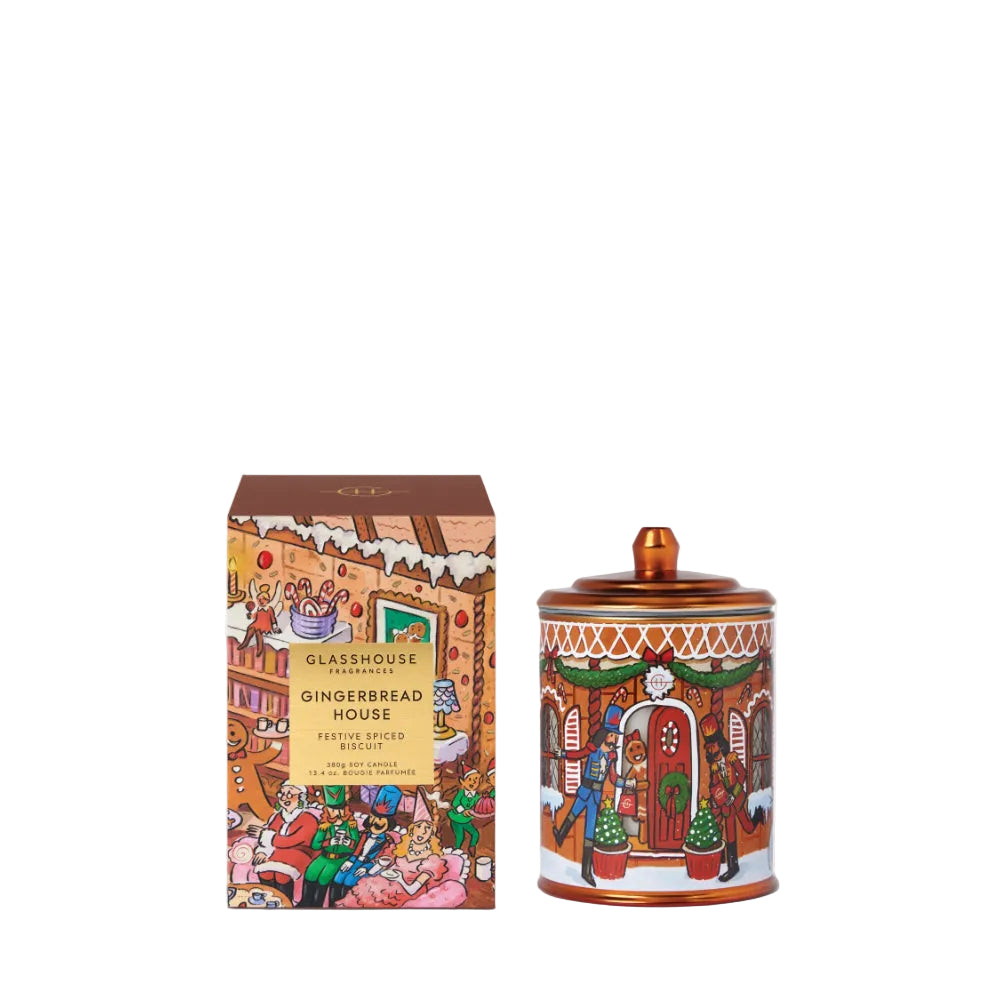 A Gingerbread House scented candle by Glasshouse, shown with its illustrated packaging box and the amber glass jar with lid. The product features a whimsical, colorful illustration of a gingerbread house scene.