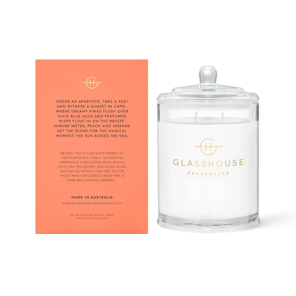 The back of a glasshouse Fragrances candle  packaging with text and clear "Sunsets In Caprion" candle on a white background. 