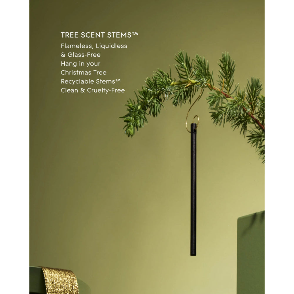 A black cylindrical hanging Christmas tree scent stem displayed against a muted olive-green background, with a pine branch draped across the top and white product text on the left reading 'TREE SCENT STEMS™'.
