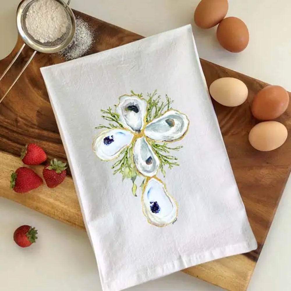 White towel with oyster design on a wooden cutting board with eggs and strawberries.