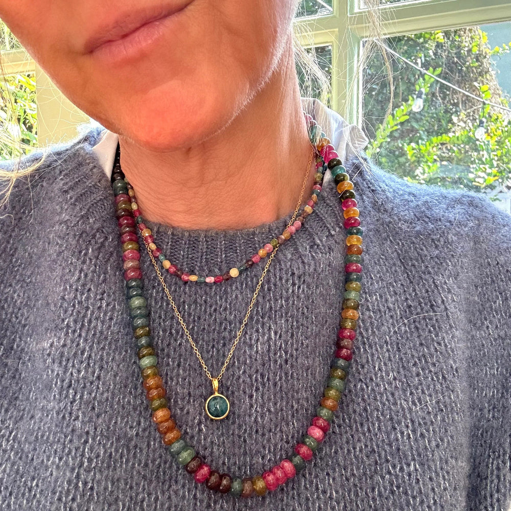 A close-up of a person wearing layered necklaces. 