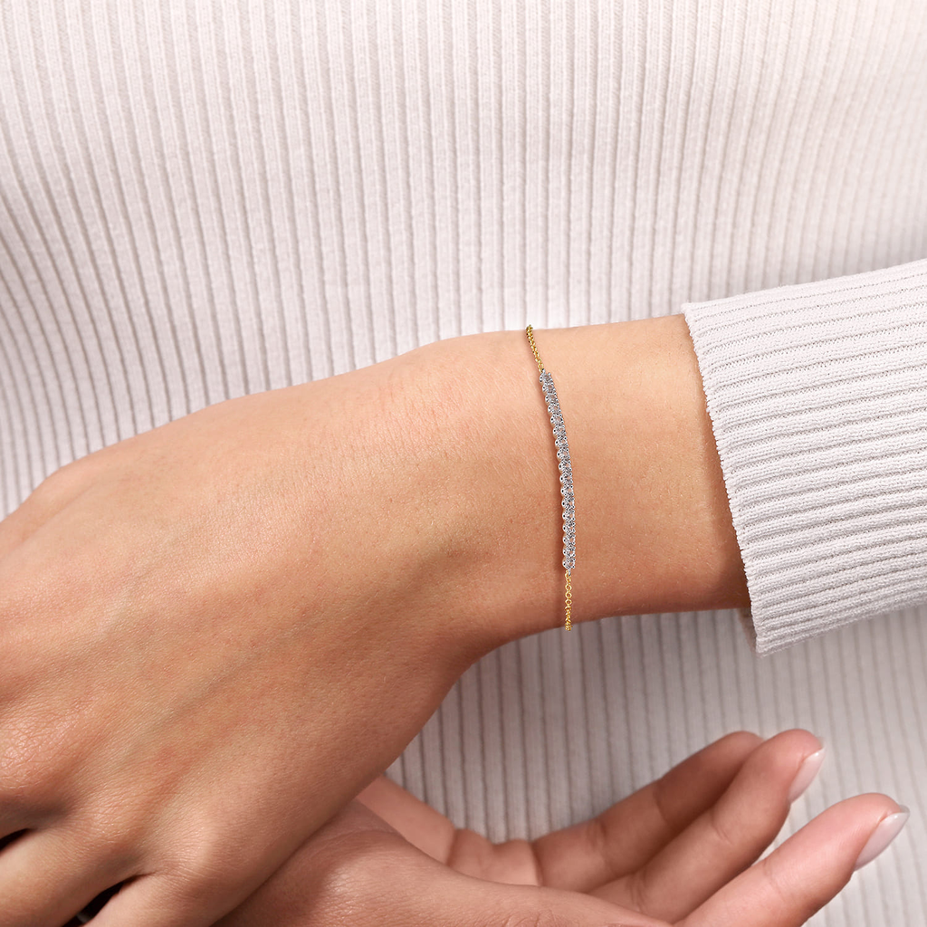 model wearing gold bracelet with white stones on white background