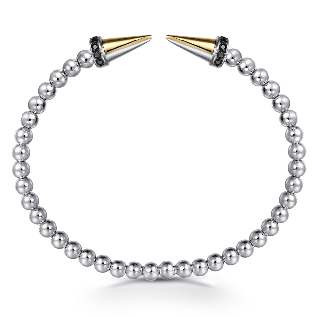 Silver beaded bracelet with gold and silver spike ends on a white background