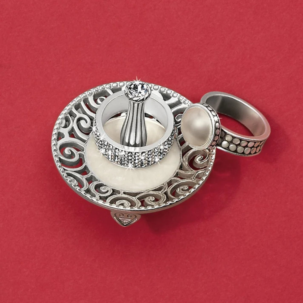 Silver ring with intricate design on a red background