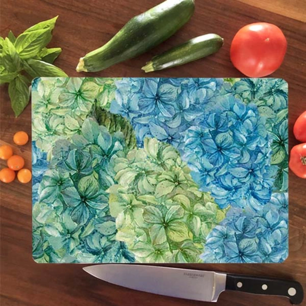 Floral-patterned cutting board on a wooden surface with vegetables and a knife.