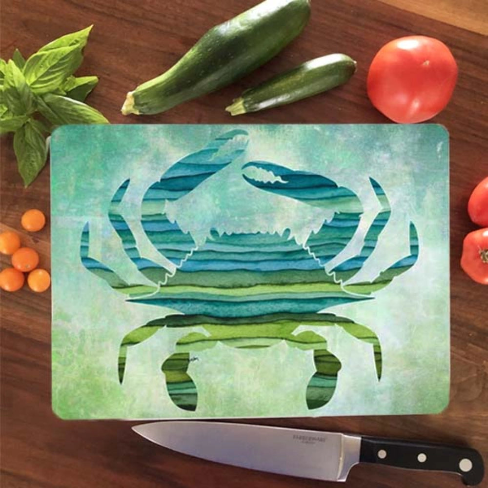 Glossy cutting board with a crab design on a wooden surface with vegetables.