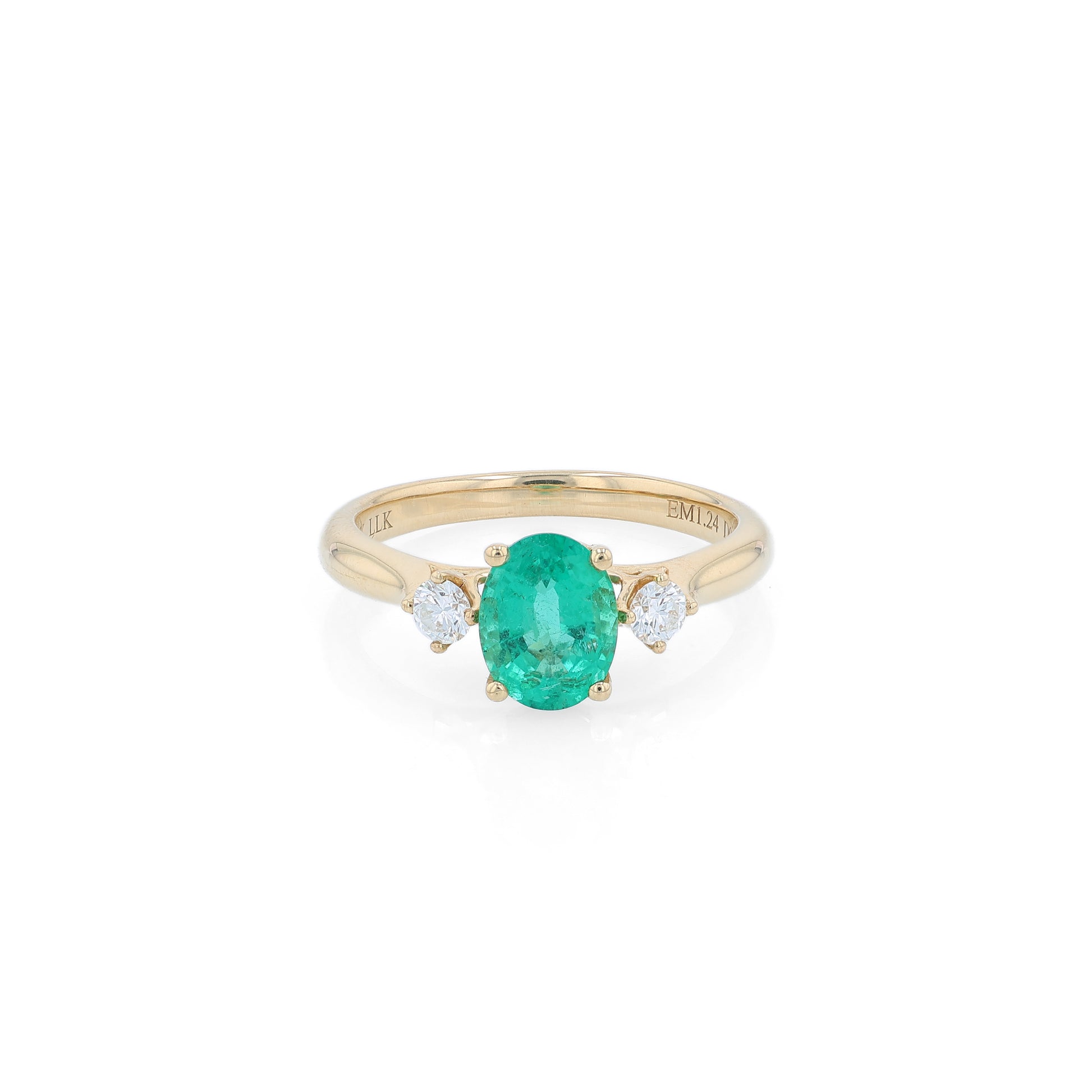 Gold ring with an oval emerald center and diamond sides on a white background