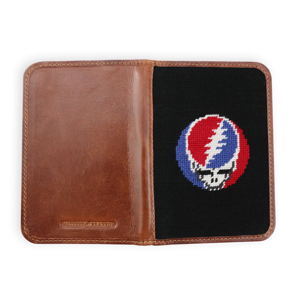 An open brown leather golf scorecard cover on a white background, featuring a black needlepoint panel on the right side with a red, white, and blue Steampain embroidered Grateful Dead skull design.