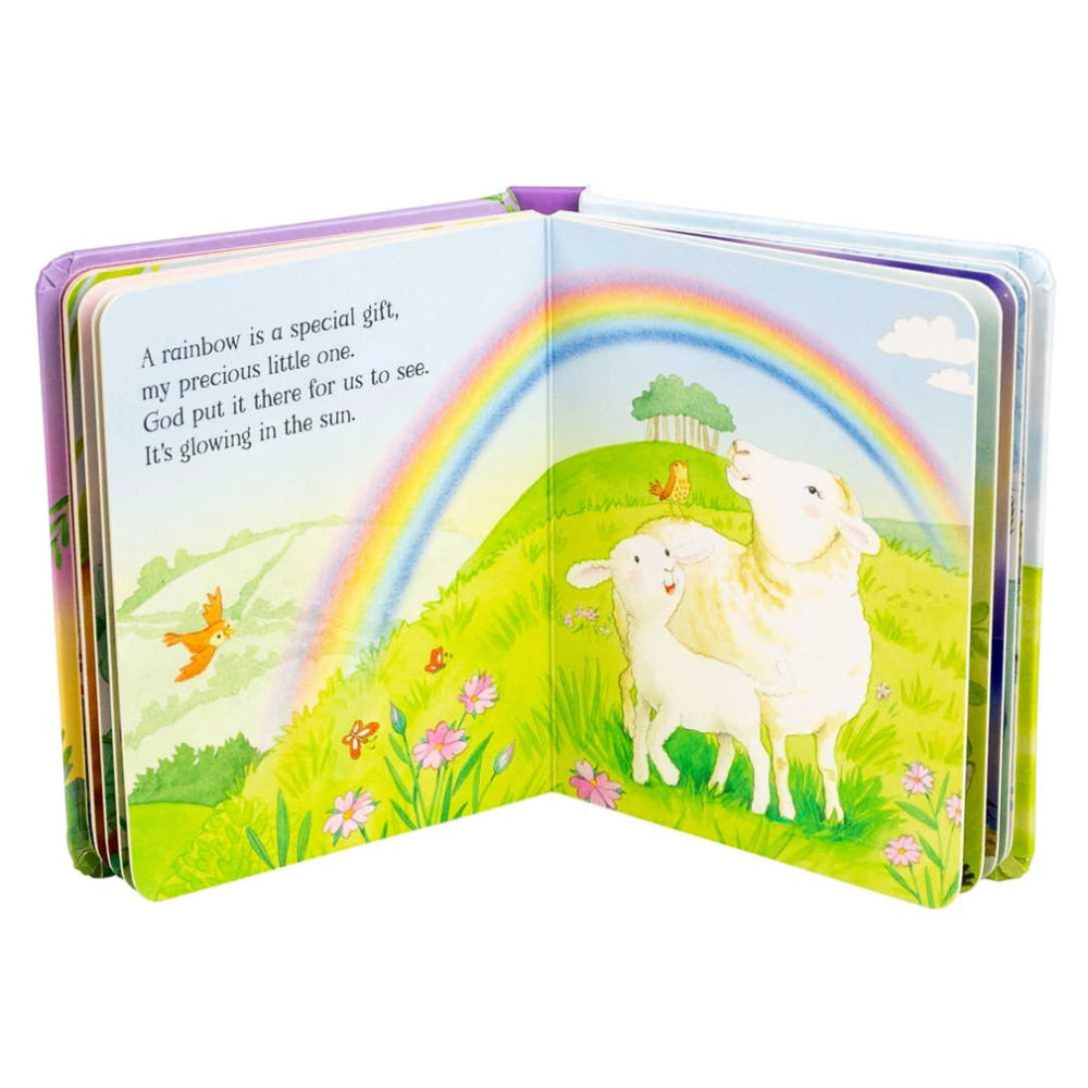 Children's book open to a page with a rainbow and sheep illustration on a white background