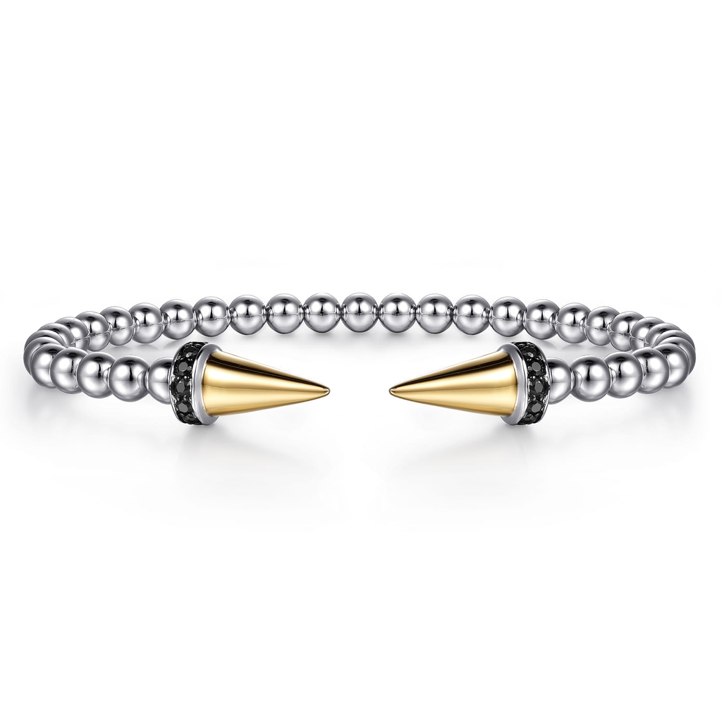 Silver beaded bracelet with gold spike ends on a white background