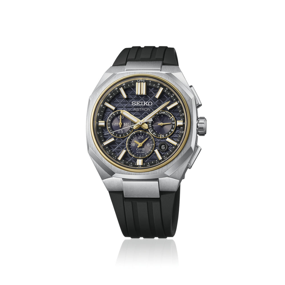 A Seiko chronograph watch with a silver-tone stainless steel case, a dark blue textured dial with gold-tone hands and markers, and a black rubber strap, shown on a white background with a subtle reflection.