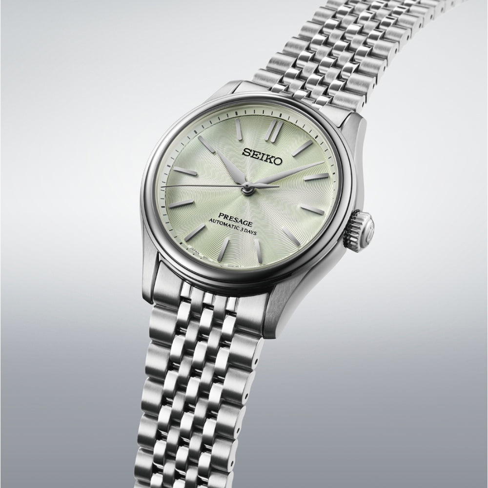 A Seiko wristwatch with a silver stainless steel case and link bracelet, featuring a pale green dial and silver-tone hour markers.