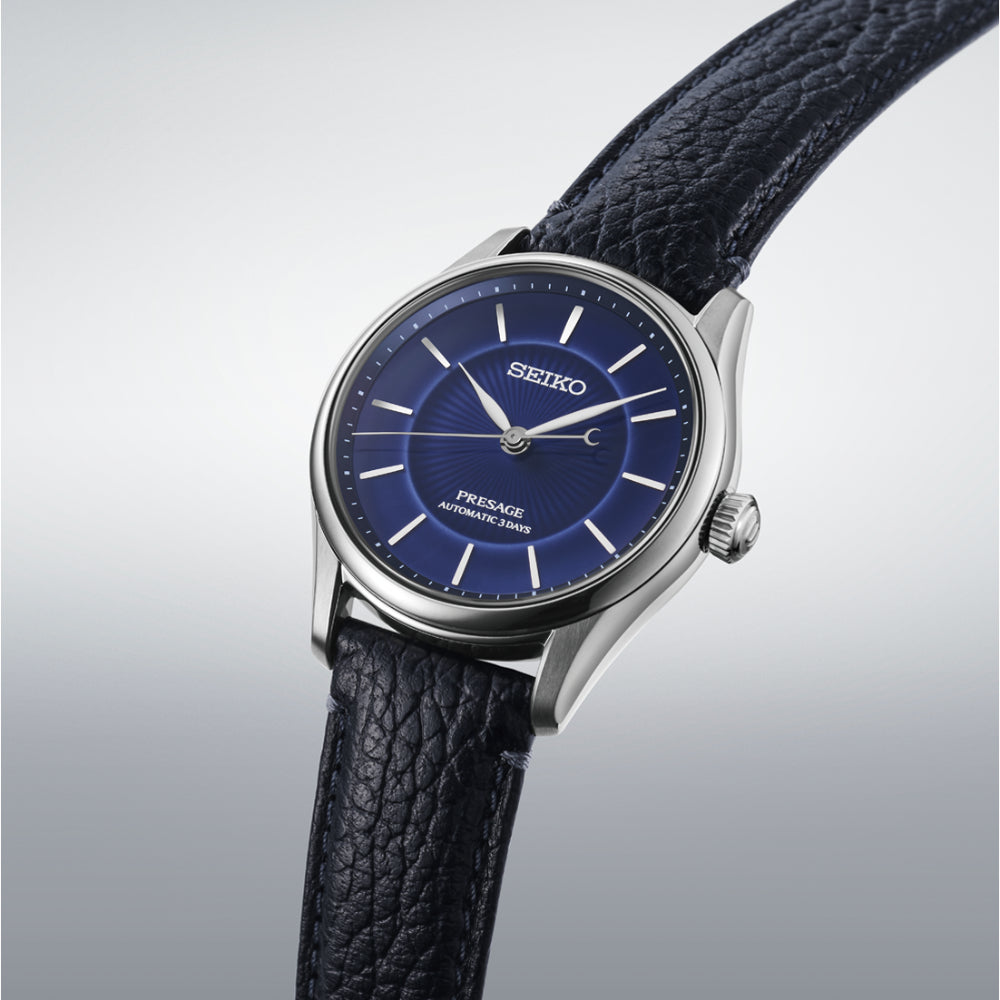 Seiko watch with blue dial and black leather strap on a light gray background