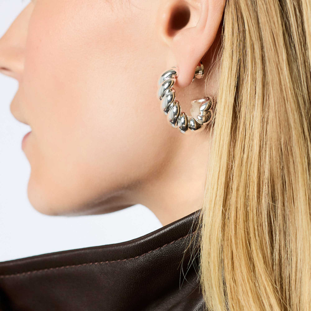 Close-up of a person wearing a silver hoop earring with a blurred background