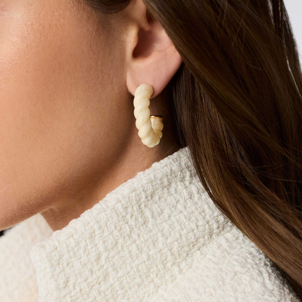 Close-up of a person wearing pearl earrings with a neutral background