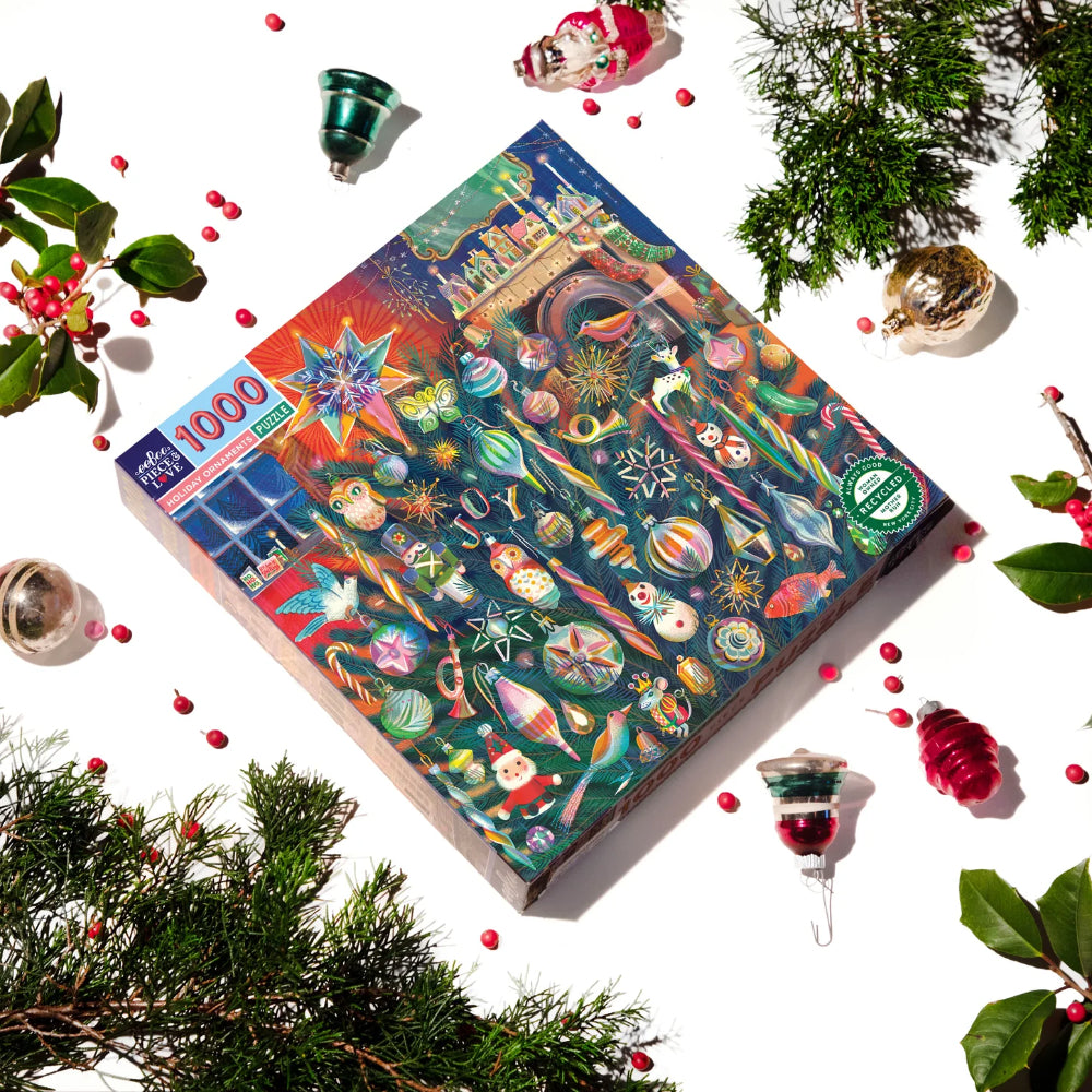 Jigsaw puzzle box with Christmas-themed design surrounded by festive decorations on a white background