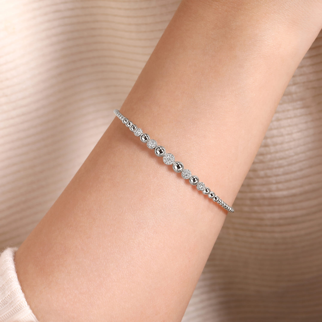 girl wearing silver beaded bangle bracelet with clear stones on natural background