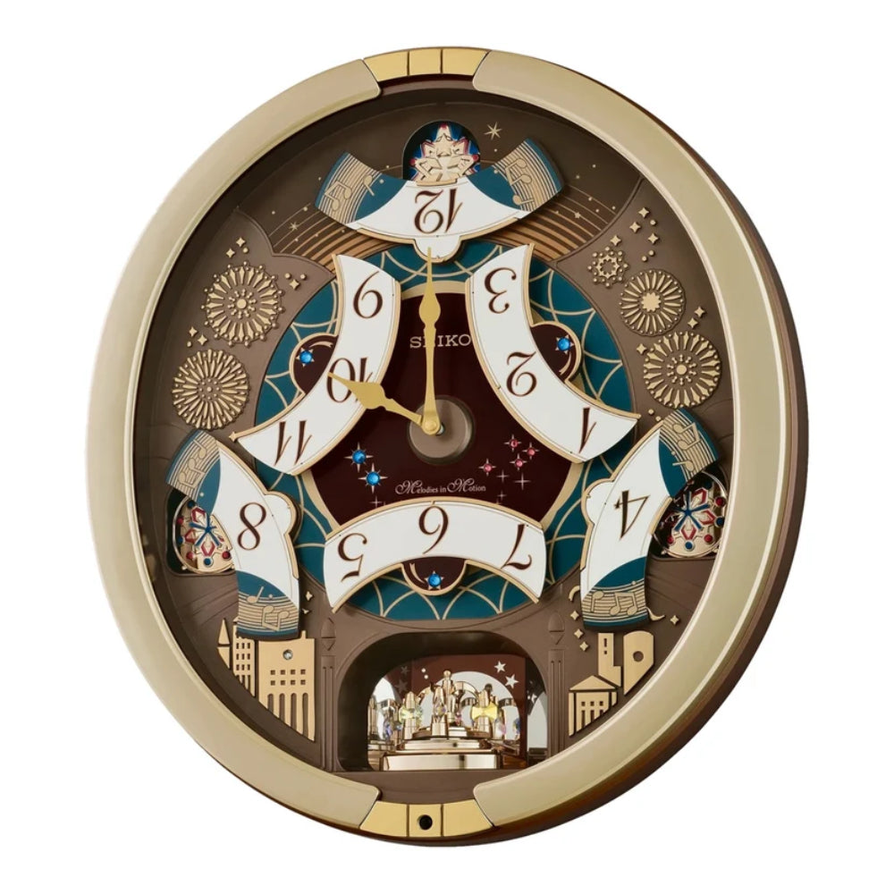 A round, multi-layered Suiko wall clock with a gold-toned frame and a complex, multi-level design featuring five rotating tiers with Japanese numerals, fireworks, and architectural details, set against a plain white background.