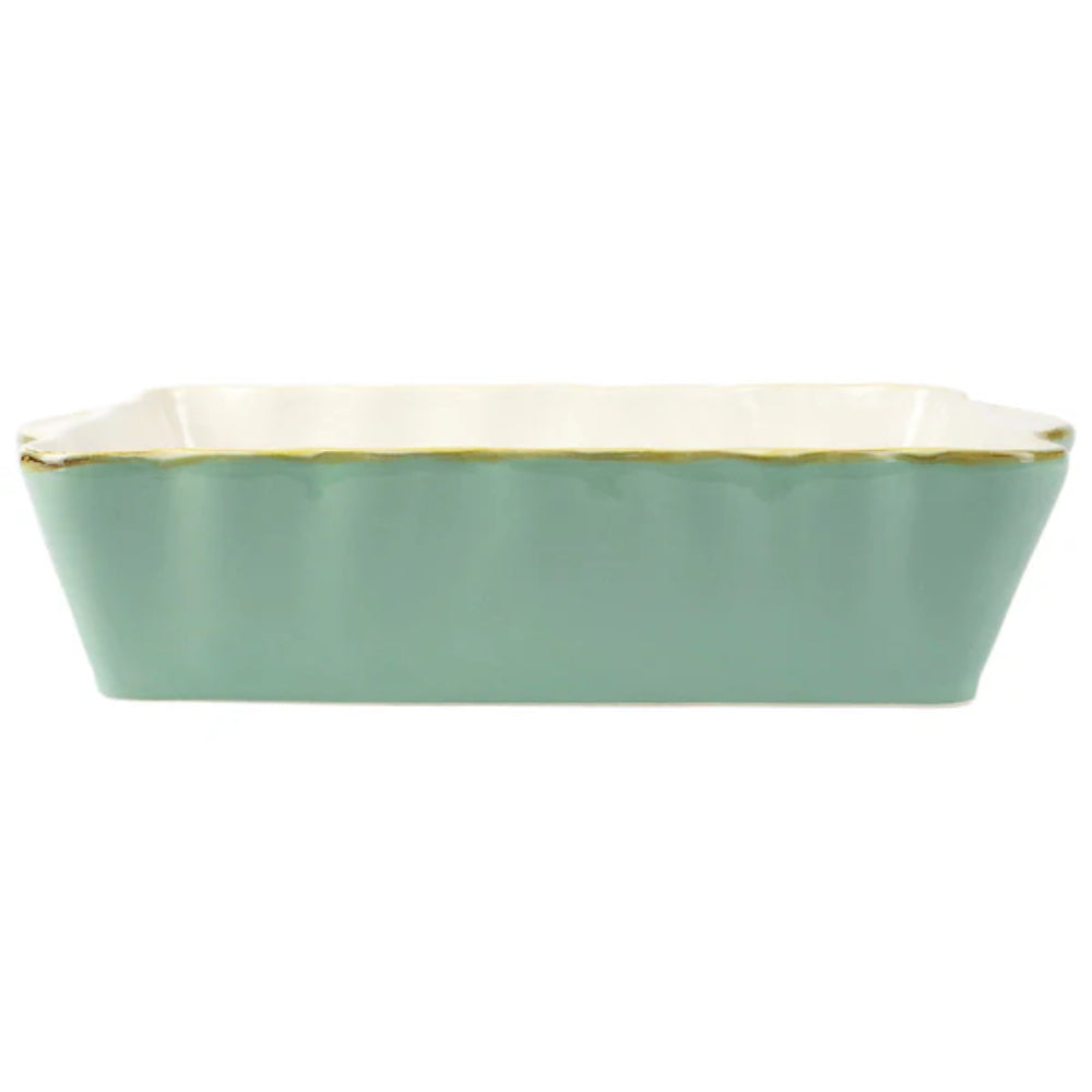 Large aqua colored  rectangular baking dish with a scalloped edge and gold rim with a white intior on a white background