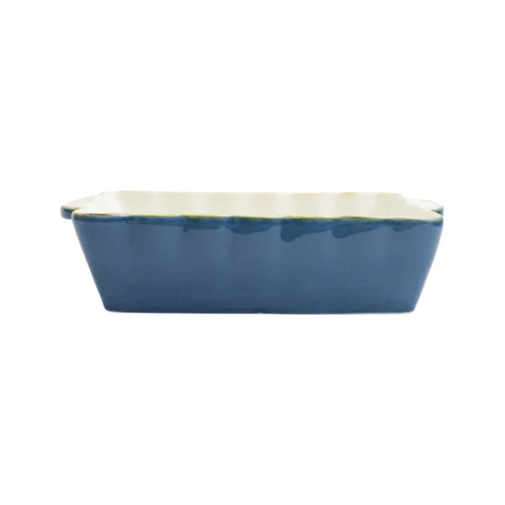A medium blue rectangular stoneware baker with scalloped edges and gold rim with a with interior