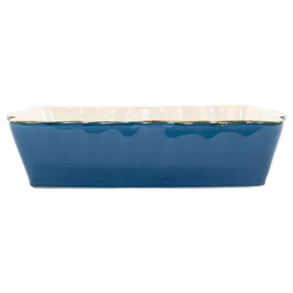 Large blue rectangular baking dish with a scalloped edge and gold rim with a white intior on a white background